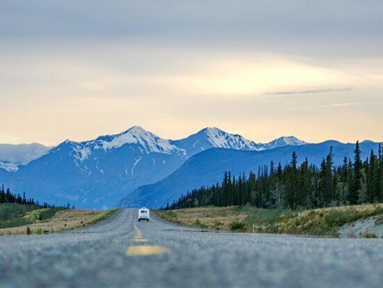 Car driving down the road at sunset in Alaska.